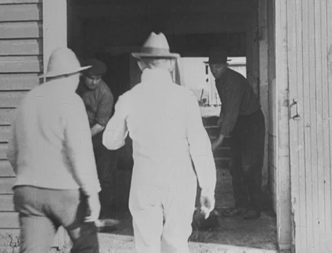 1920s - Men talking, sweeping barn Stock Footage 166578003