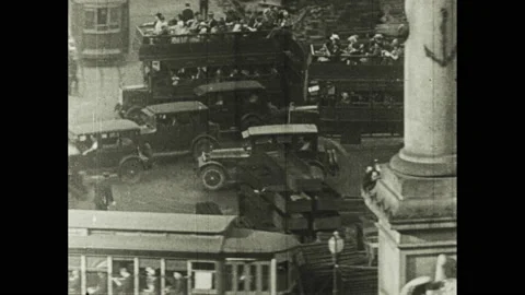 1920s: Men work in auto assembly plant. Cars and people navigate crowded city Stock Footage 152741677