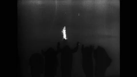 1920s: People gesture at fire. Title card. Flashes of light. Man pulls rope to Stock Footage 162328068