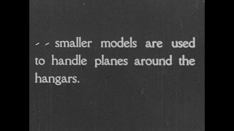 1920s: A small tractor pulls a propeller plane past an airport hangar. A tractor Stock Footage 82921969