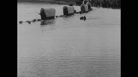 1923 - In this silent western, oxen pull wagons in a caravan across the Missouri Stock Footage 214335560