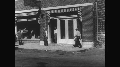 1929: Men walk to and from a paint and wallpaper store, loading a cart with Stock Footage