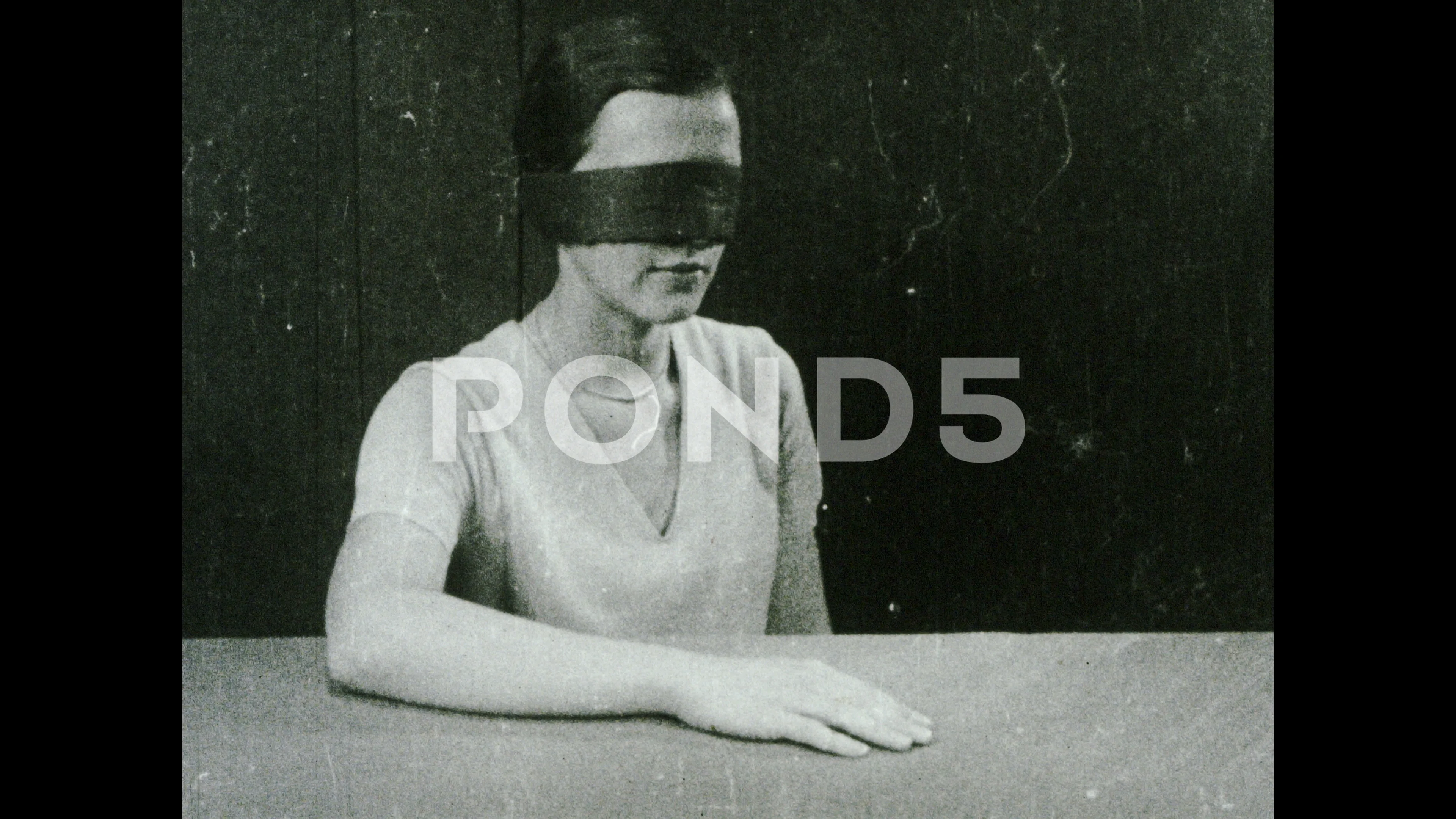 blindfolded woman sitting at a table - SuperStock