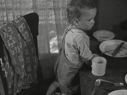 1930s: Boy eats bread at kitchen table Stock Footage 231920068