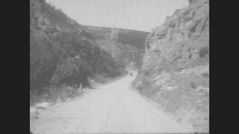 1930s: Car Drives Down Winding Mountain Road. Man Stands In Desert. Stock Footage