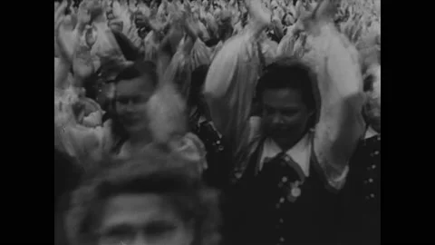 1930s: Crowd of people clap and cheer. Ships at port. Cargo is transferred at Stock Footage 148227525