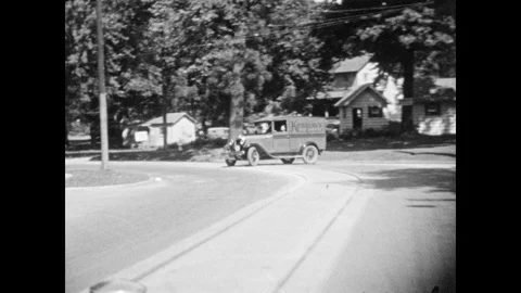 1930s: Driving down road, pull into gas station. Driving down road by large body 스톡 동영상 87722534