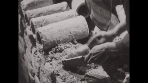 1930s  ENGLAND: Several men work on a mud-brick structure in an ancient setting. Stock Footage 337200974