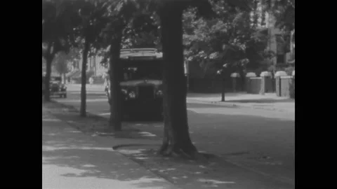 1930s: Group of children run down sidewalk. School bus pulls up to sidewalk. Stock Footage 148225791