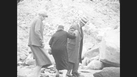 1930s: Man Helps Women Climb Over Rocks. Man Standing On Peak, Pan Across Stock Footage