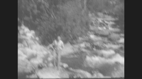 1930s: Man Hops Onto Rocks In River, Waves Arms. Car Drives Along Mountainside. Stock Footage
