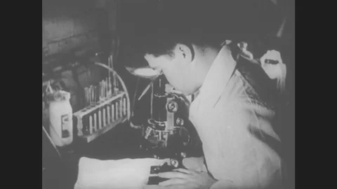 1930s: Man Looks Through Microscope. Microscopic Organisms Move Around Under Stock Footage