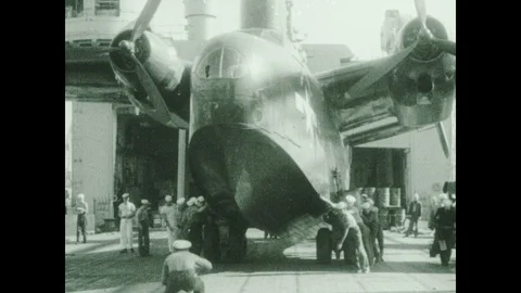 1930s: Men pull airplane onto deck.  Man salutes.  Crowd waves to departing Stock Footage 119482359