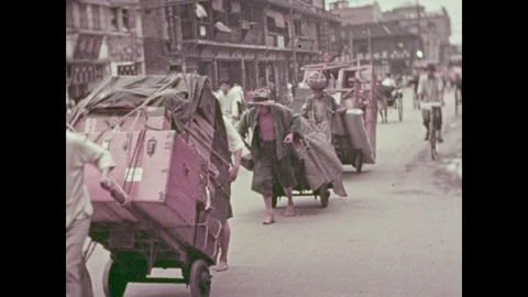 1930s: Men push and pull heavy loads.  Men run down the street with rickshaws. Stock Footage 87044356