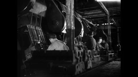 1930s: Men remove engine blocks, place them on conveyor belts. Man places gauge Stock Footage 93278777