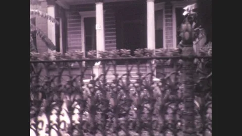 1930s: Ornate fence in front of a house with a porch. Large boat tied to a dock Stock Footage