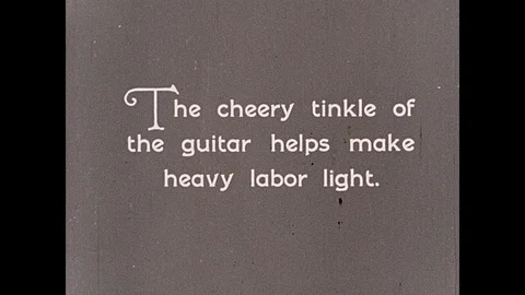 1930s: Philippines: workers in rice field near village. Man plays guitar under Stock Footage 94746499