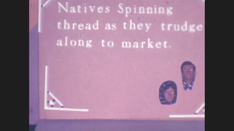 1930s: Sign reads Natives spinning thread as they trudge along to market, with Stock Footage