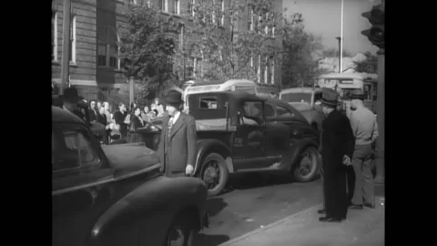 1930s - Two men argue over car trouble on a busy city street. Stock Footage 157286410