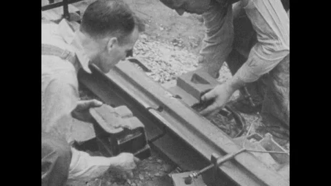 1930s: Two men attach metal container to railroad track. Magnesium burning Stock Footage 99060127