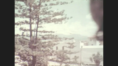 1930s: View from a height of white adobe building. Car travels down walled road Stock Footage