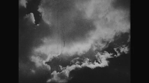 1930s: View of sky. Rain falls on soil. View of sky. Pan across water on field. Stock Footage