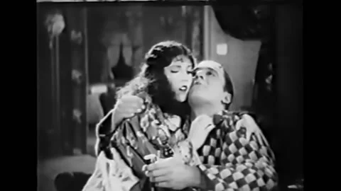 1938 - In this silent comedy, a married couple hugs and kisses while the wife Stock Footage 232883078