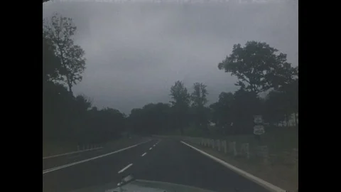1940s, 1950s: Car drives down winding mountain road by lake, truck passes by. Stock Footage
