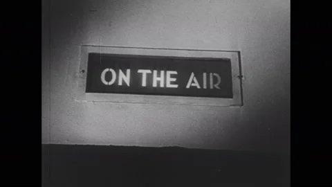 1940s: On Air sign. Man sits in radio control room. Man adjusts radio equipment. Stock Footage