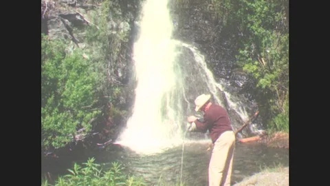 1940s: Alaska: Man Stands By Waterfall. Man Collects Water From Waterfall Pool. Stock Footage
