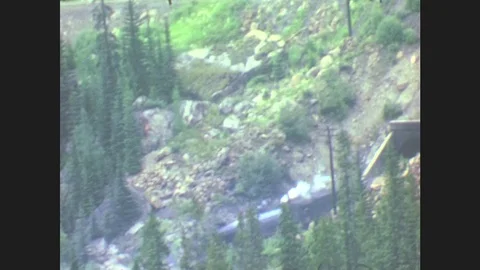 1940s: Alaska: Steam Train Appears From Tunnel. Waterfall And Rocks. View Across Stock Footage