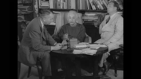 1940s: Albert Einstein, Leo Szilard and man are seated around table, man reads Stock Footage 158967662