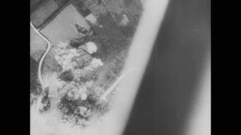 1940s: Bombs explode on ground. Planes drop bombs. Ships fire cannons. Assault Video stock 150349169