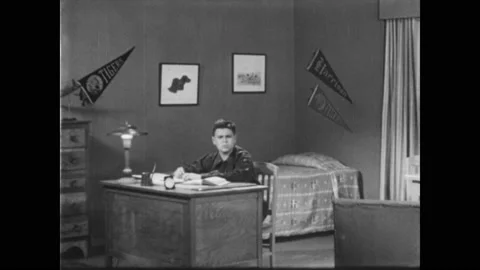 1940s: Boy slams down his hand on a notebook, curses to himself. He looks around Stock Footage 205078533