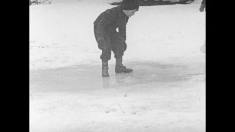 1940s: Boy stands on patch of ice.  Child runs and slips on ice. Stock Footage 103559792