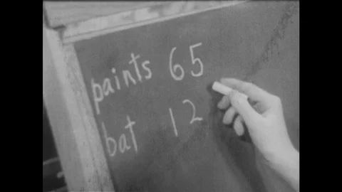 1940s: Boy writes value of objects on chalkboard in living room. Boy smiles. Boy Stock Footage 116053168