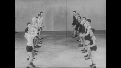 1940s: Boys stand in two rows across each other and practice overhand sets. Ball Stock Footage