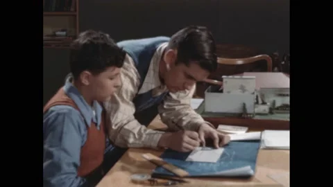 1940s: brothers work on homework at dining room table. Boy draws line with Stock Footage 189945304