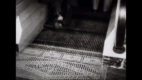 1940s: Bustling crowd of shoppers ride the escalator in a department store. Stock Footage 113940625