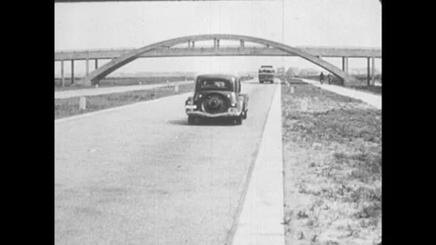1940s: Cars and bus drive down modern highway. Electric train runs along busy Stock Footage