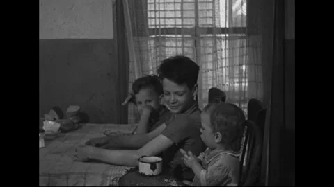 1940s: Children energetically clearing the cluttered kitchen table, while a Video stock 157777544