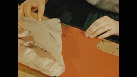 1940s: Close up, scissors cut thread on pattern. Hands lift pattern from fabric. Stock Footage 152738995