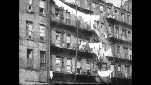 1940s: Clothes hang from lines outside tenement building. People walk along Vídeos de archivo 82730677