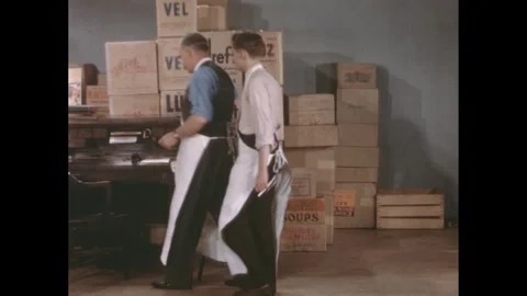 1940s: A desk before boxes of merchandise stacked against a wall. Man and young Stock Footage 280053697
