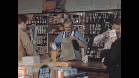 1940s: Employees in grocery store pack bags. Employee ringing up groceries for Stock Footage 170677756