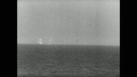 1940s: Explosion in water. Ship cannons fire. Smoke and explosions. Plane drops Stock Footage 138333737