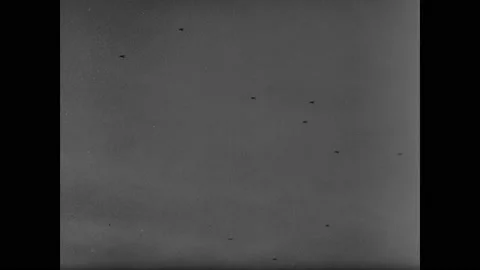 1940s: Explosions on ground.  Planes fly overhead.  Cannons fire into air. Stock Footage 147602612