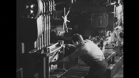 1940s: A factory worker operates a large machine in a 1940s industrial setting. Stockbeeldmateriaal 279748006
