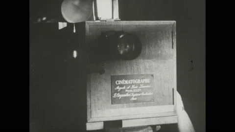 1940s: Film flickers in Lumiere projector. Man cranks handle on projector. Stock Footage