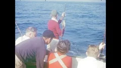 1940's: Woman unhooks flounder from fishing line; fisherman